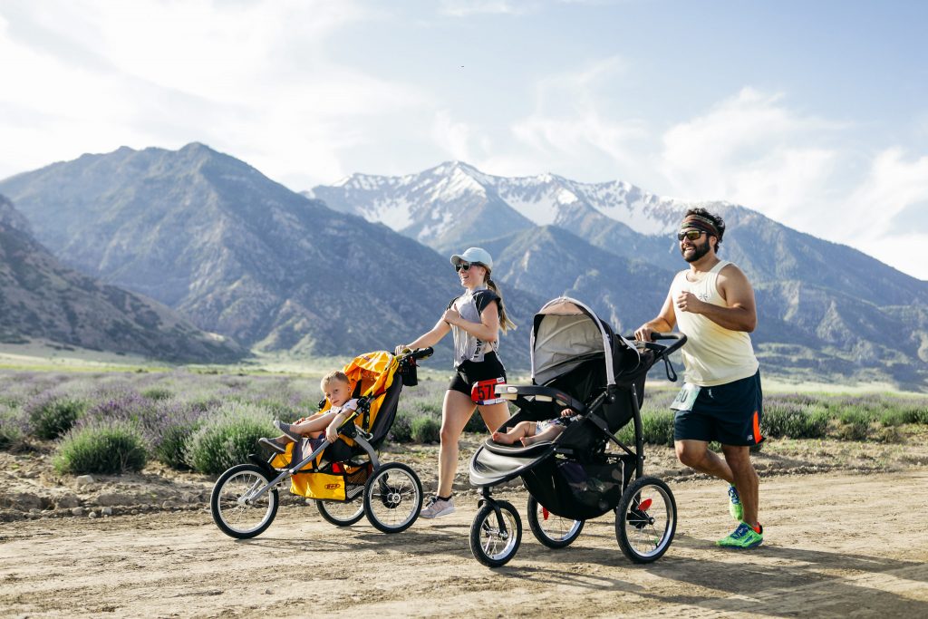 Mutter und Vater mit Kindern im Buggy joggen